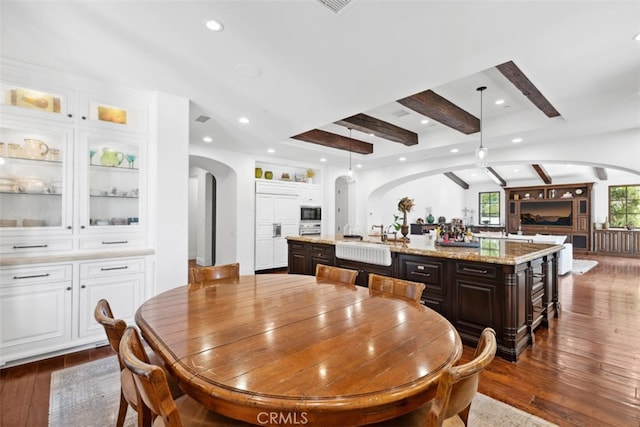 dining space with beam ceiling and dark wood-type flooring