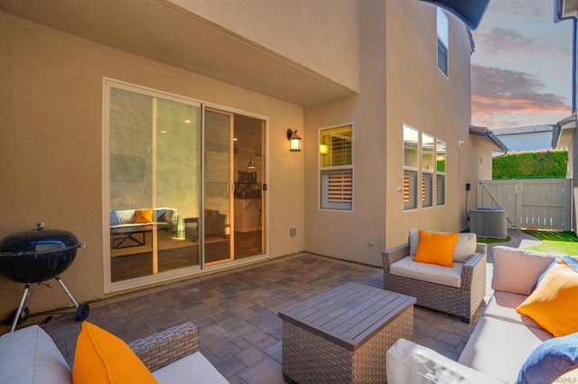 patio terrace at dusk featuring outdoor lounge area and central AC unit