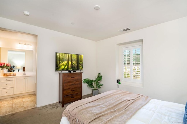 bedroom with connected bathroom and light carpet