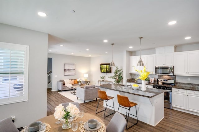 kitchen with decorative light fixtures, white cabinetry, an island with sink, and appliances with stainless steel finishes