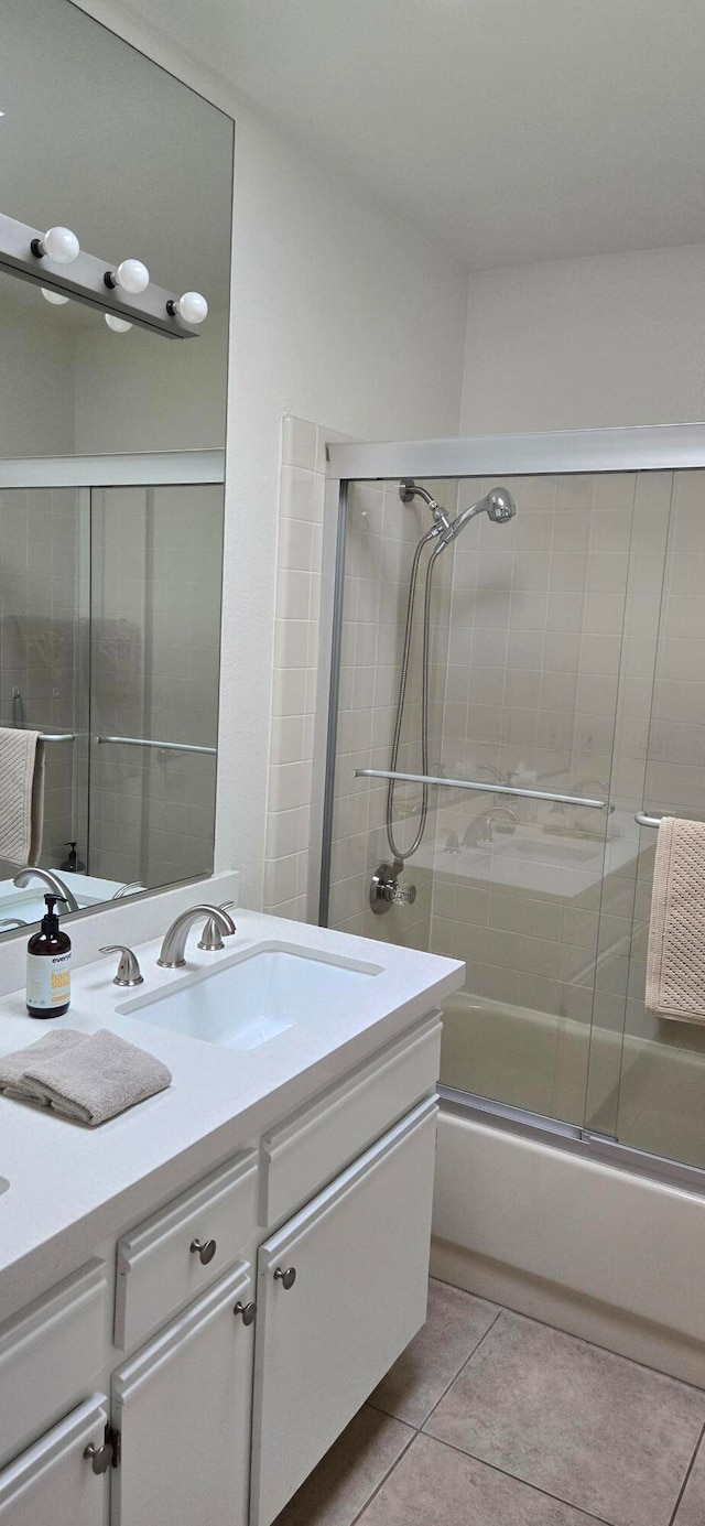 bathroom featuring tile patterned flooring, enclosed tub / shower combo, and vanity