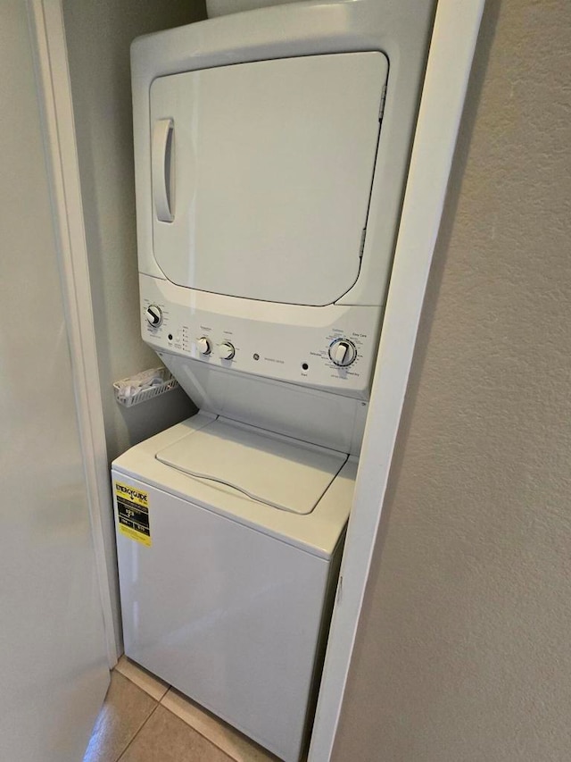 laundry area featuring stacked washer and dryer and light tile patterned floors