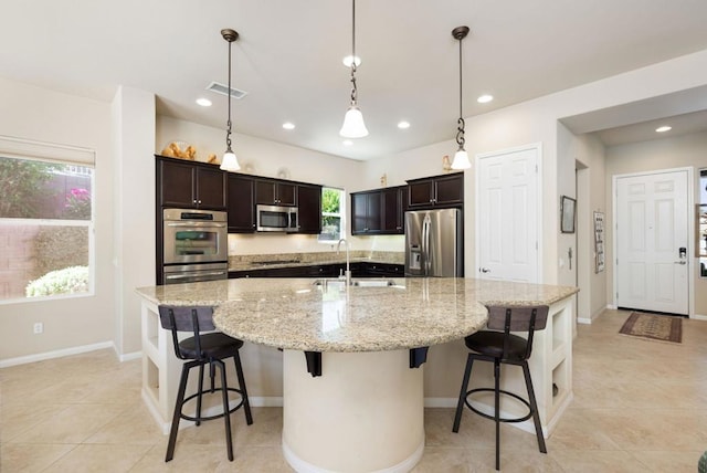 kitchen with sink, decorative light fixtures, a kitchen breakfast bar, a large island with sink, and appliances with stainless steel finishes