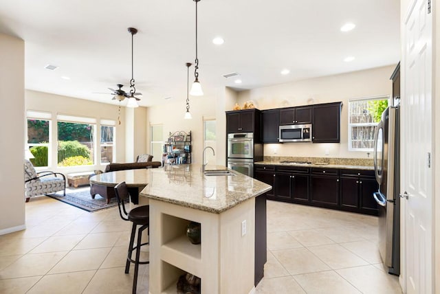 kitchen featuring a kitchen island with sink, a breakfast bar area, stainless steel appliances, pendant lighting, and sink