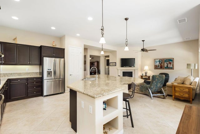 kitchen featuring sink, decorative light fixtures, ceiling fan, stainless steel fridge, and a breakfast bar