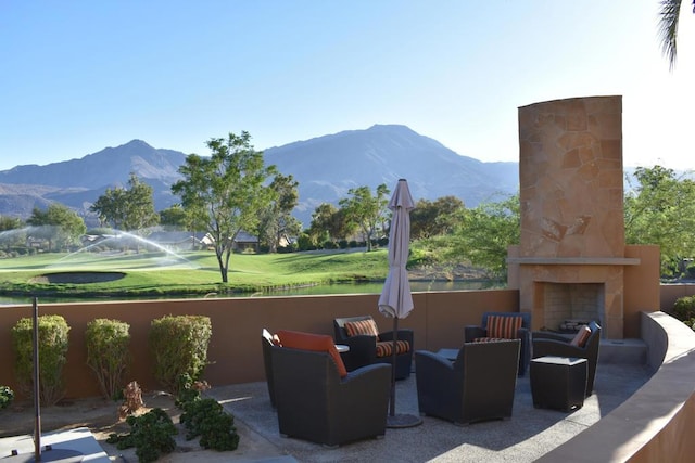 view of patio with a mountain view and an outdoor stone fireplace