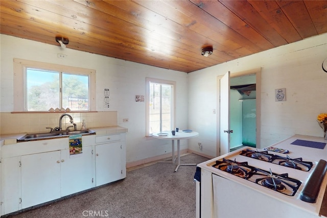 kitchen with white cabinets, light colored carpet, gas range gas stove, and a healthy amount of sunlight