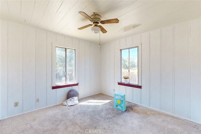 spare room featuring ceiling fan, light colored carpet, and plenty of natural light