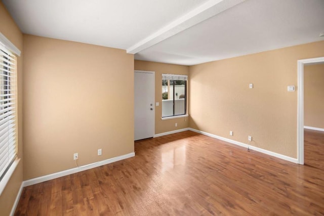 empty room featuring beam ceiling and hardwood / wood-style floors