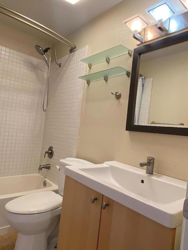 full bathroom featuring tiled shower / bath, vanity, and toilet