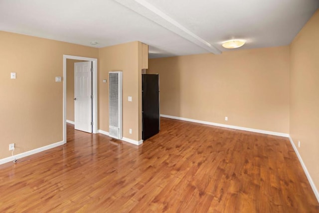 unfurnished room with hardwood / wood-style floors and beam ceiling