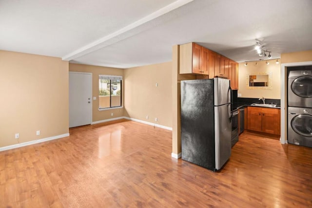 kitchen with sink, stainless steel fridge, stacked washer / drying machine, light hardwood / wood-style floors, and track lighting