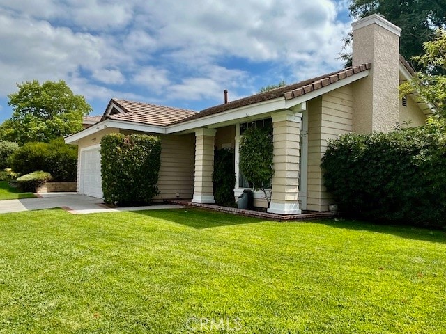 back of property featuring a garage and a yard