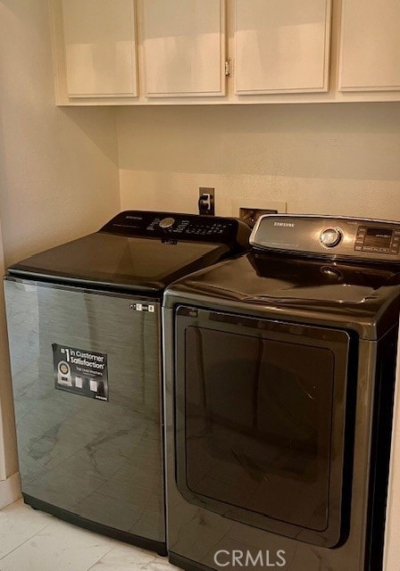 laundry area with washer and clothes dryer, cabinets, and light tile patterned floors