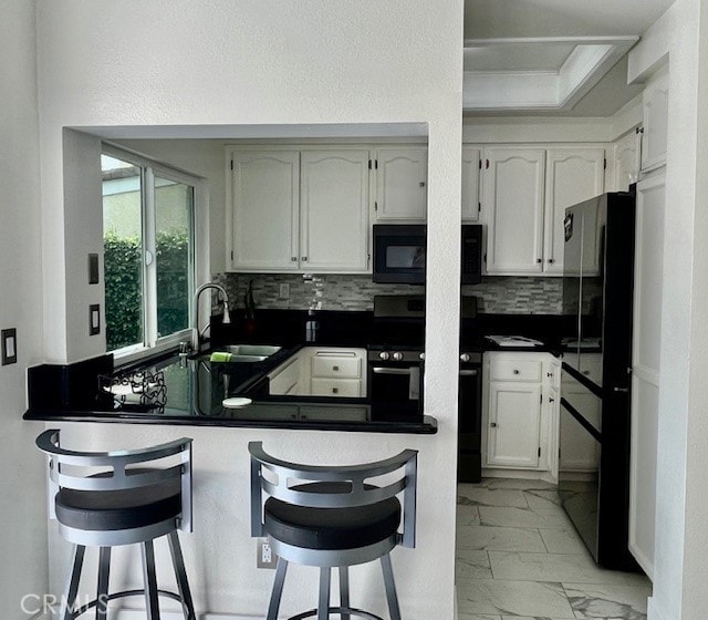 kitchen with a breakfast bar, decorative backsplash, and black appliances