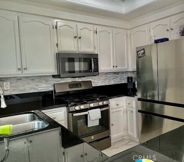 kitchen with white cabinets, appliances with stainless steel finishes, backsplash, and sink