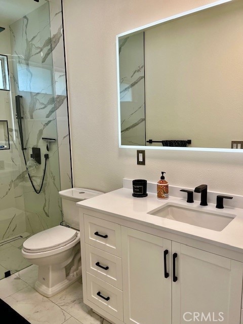 bathroom with a shower with shower door, vanity, and toilet