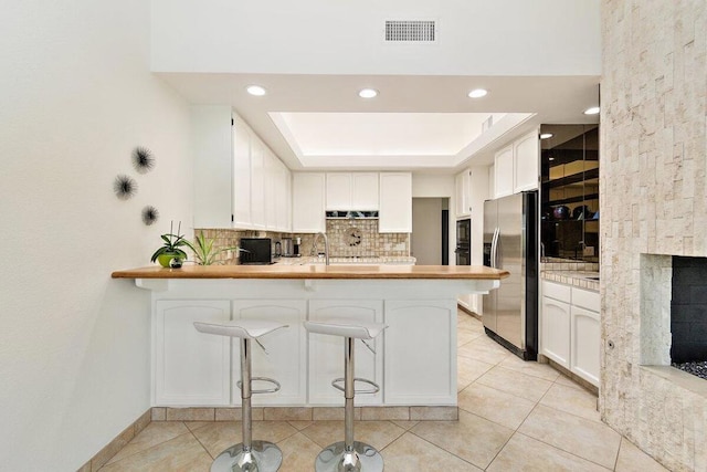 kitchen with kitchen peninsula, black appliances, a breakfast bar, and white cabinets