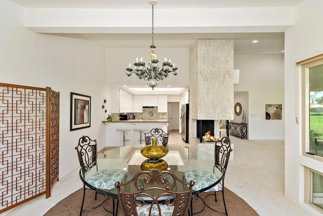 carpeted dining area featuring a large fireplace and a chandelier