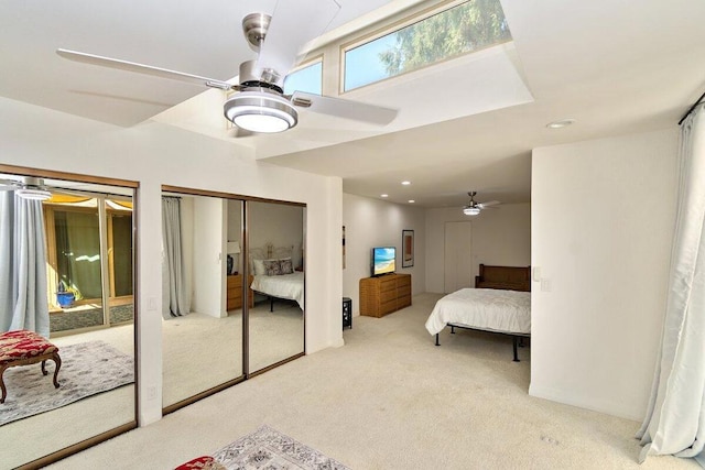 bedroom featuring light carpet, multiple closets, and ceiling fan