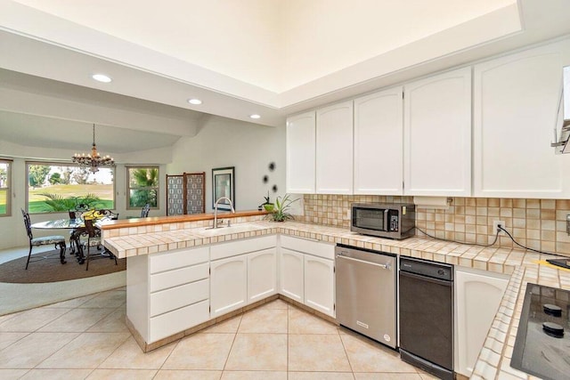 kitchen featuring white cabinets, decorative light fixtures, kitchen peninsula, and appliances with stainless steel finishes