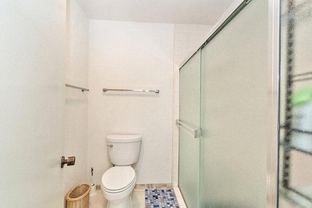 bathroom featuring a shower with shower door, tile patterned floors, and toilet