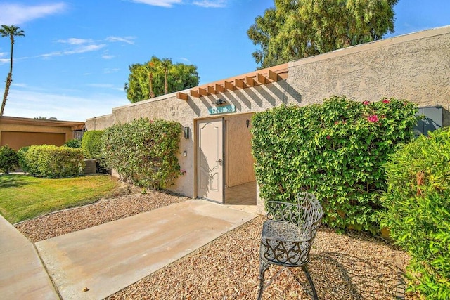 view of exterior entry featuring a patio area and a lawn