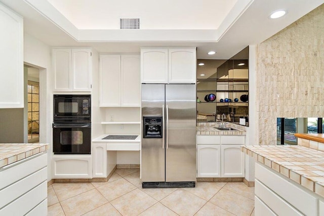 kitchen with sink, black appliances, tile countertops, and white cabinets