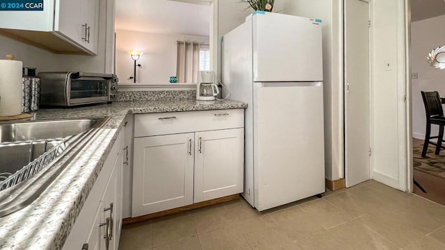 kitchen featuring white cabinetry, light tile patterned floors, and white fridge