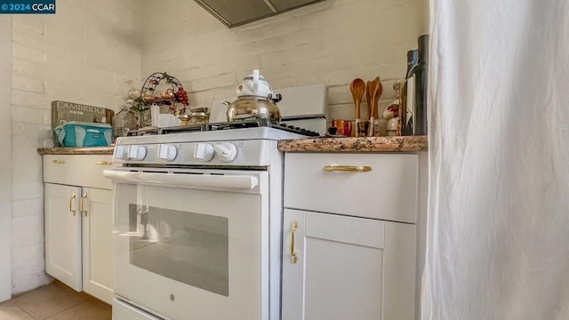 kitchen with white cabinets, white range oven, and light tile patterned floors