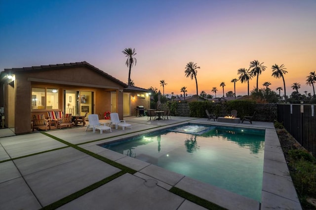 pool at dusk with a patio area