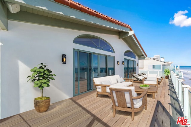 wooden deck with a water view and outdoor lounge area