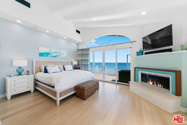 bedroom featuring vaulted ceiling with beams, light hardwood / wood-style floors, and access to outside