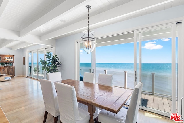 dining space with a water view, beam ceiling, light hardwood / wood-style flooring, and a chandelier