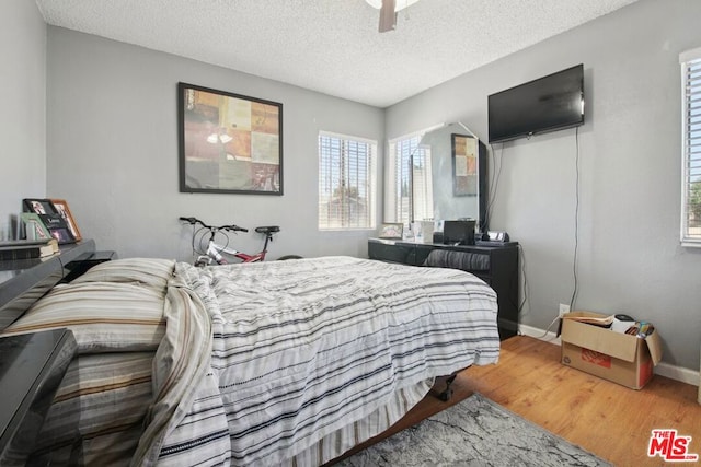 bedroom featuring ceiling fan, hardwood / wood-style floors, and a textured ceiling