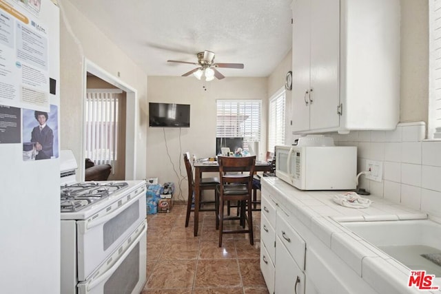 kitchen with tile counters, white appliances, white cabinetry, and decorative backsplash