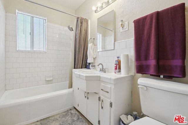 full bathroom with shower / bathtub combination with curtain, vanity, tile walls, and toilet