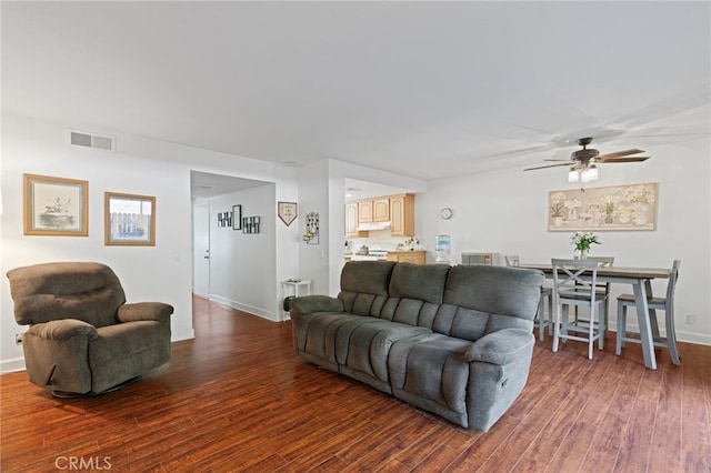 living room featuring ceiling fan and dark hardwood / wood-style floors