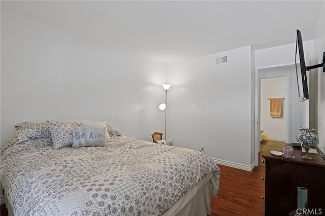 bedroom featuring dark wood-type flooring and ensuite bathroom