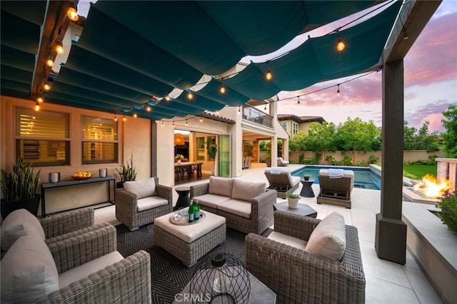 patio terrace at dusk featuring an outdoor living space and a balcony