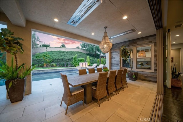 tiled dining space featuring wood walls and a skylight