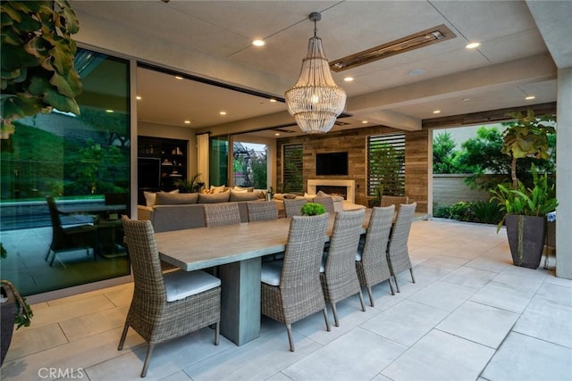 dining area featuring light tile patterned flooring, exterior fireplace, and a notable chandelier