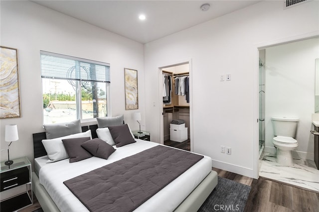 bedroom with ensuite bathroom, dark hardwood / wood-style floors, a walk in closet, and a closet