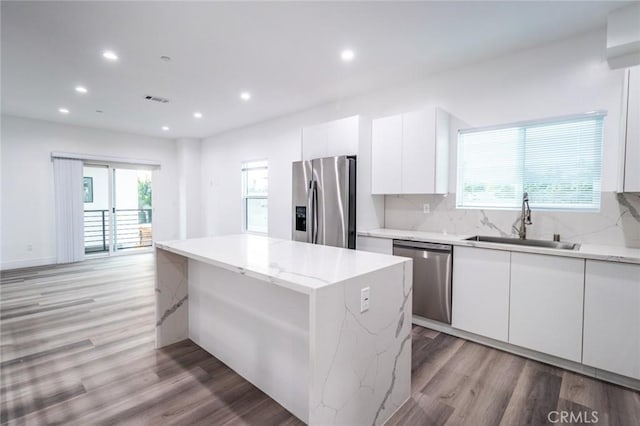 kitchen with a center island, white cabinets, sink, a wealth of natural light, and appliances with stainless steel finishes