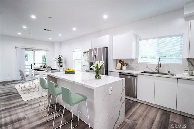 kitchen featuring white cabinets, a center island, stainless steel appliances, and sink