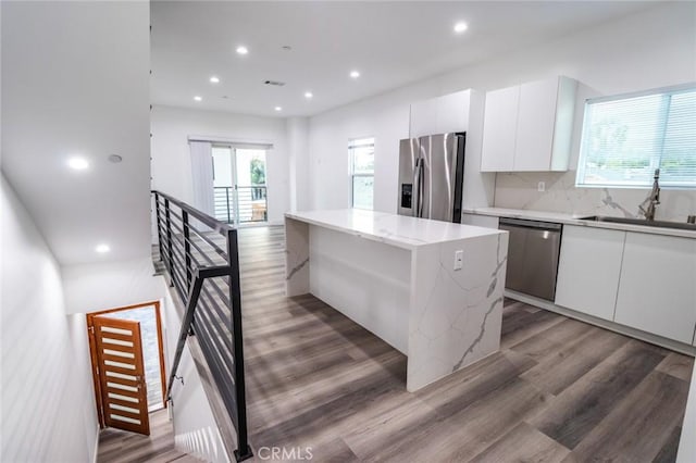 kitchen featuring white cabinets, a kitchen island, sink, and stainless steel appliances