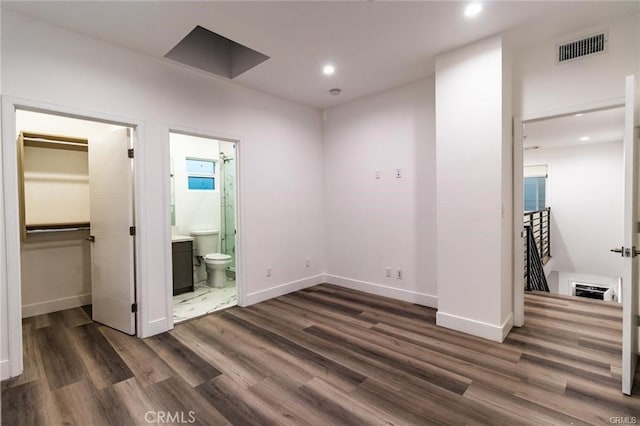 interior space with ensuite bathroom, dark hardwood / wood-style floors, a walk in closet, and a closet