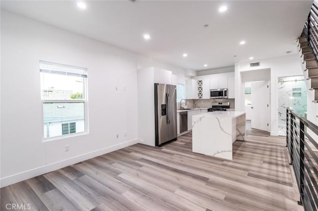 kitchen featuring stainless steel appliances, a kitchen island, sink, light hardwood / wood-style floors, and white cabinetry