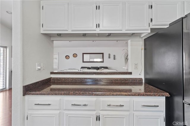 kitchen with plenty of natural light, stainless steel fridge, and white cabinetry