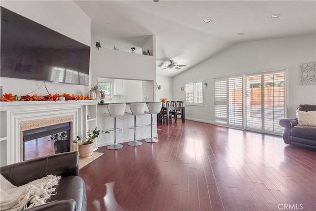 living room featuring ceiling fan, lofted ceiling, dark wood-type flooring, and a wealth of natural light